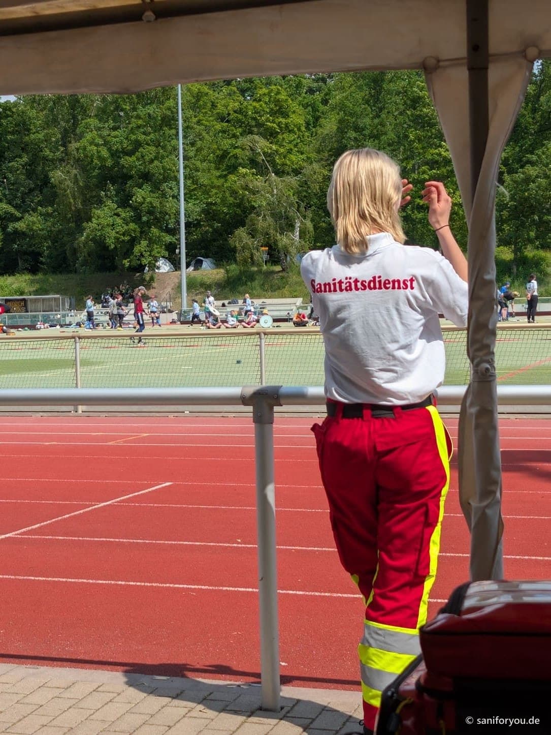 Sanitäterin in SaniForYou-Trikot beobachtet einen Wettkampf im Stadion
